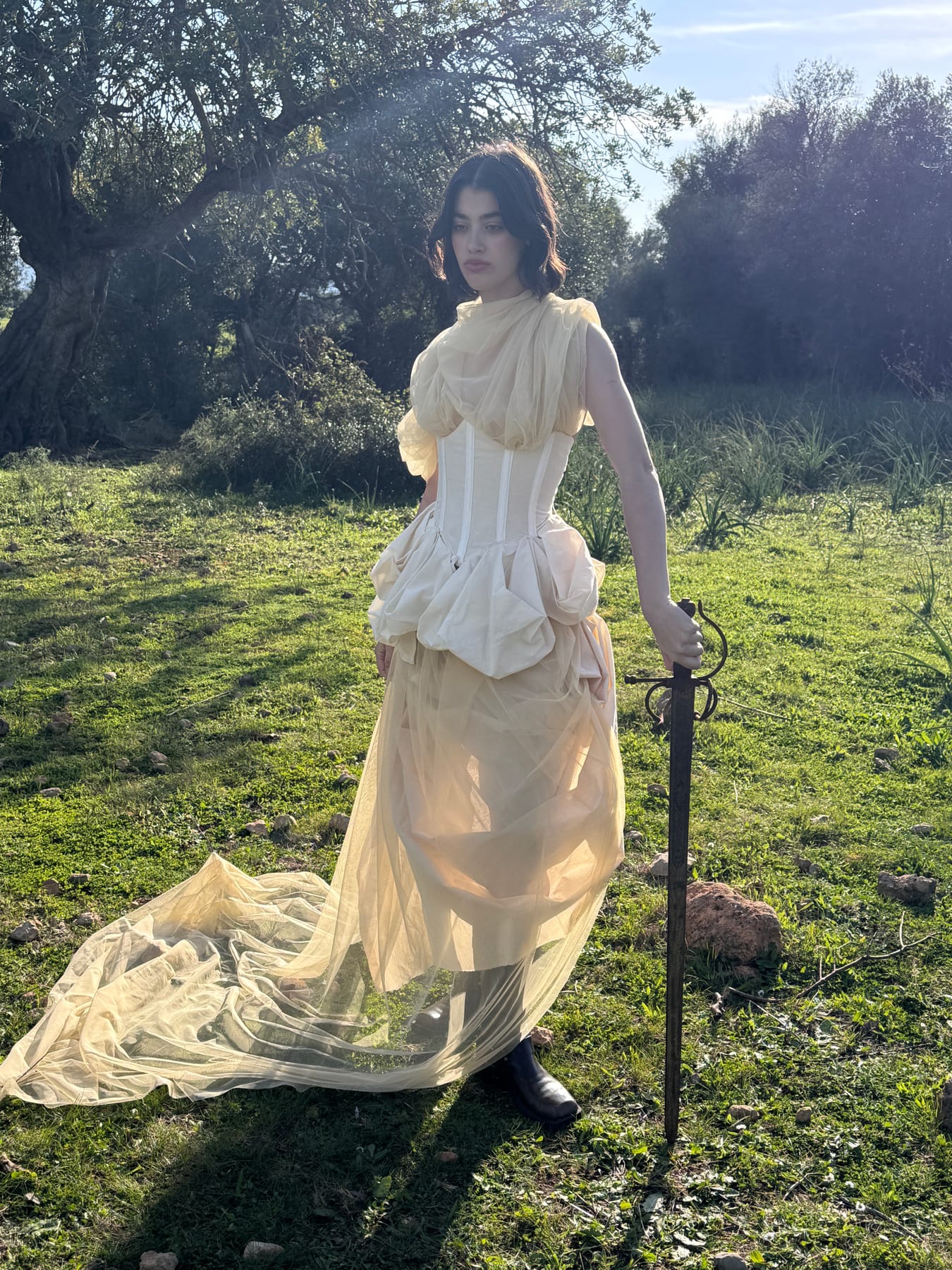 Modelo sosteniendo una espada antigua en el campo