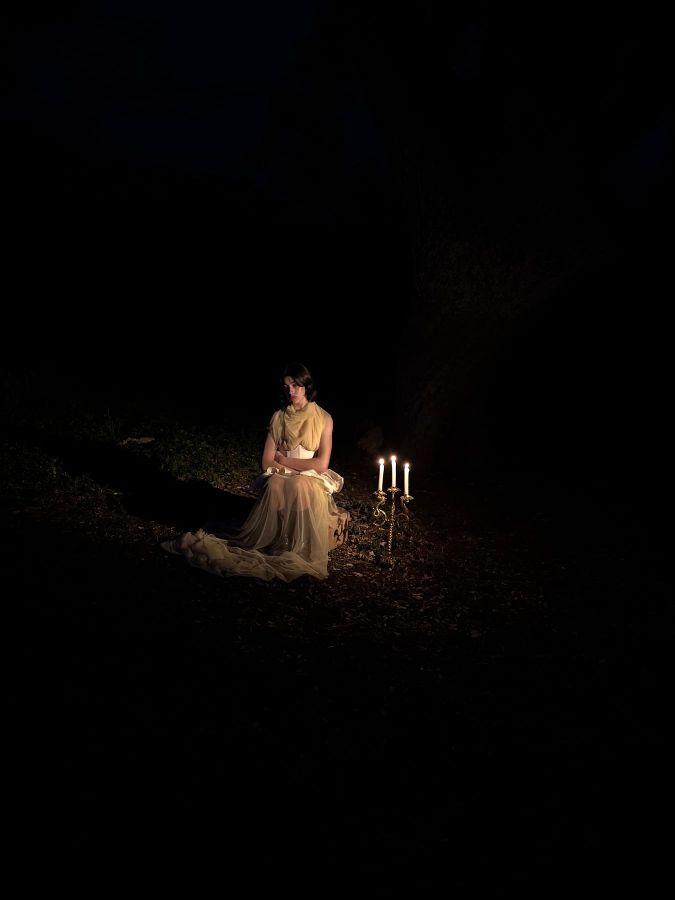 Figura iluminada por candelabros en la oscuridad