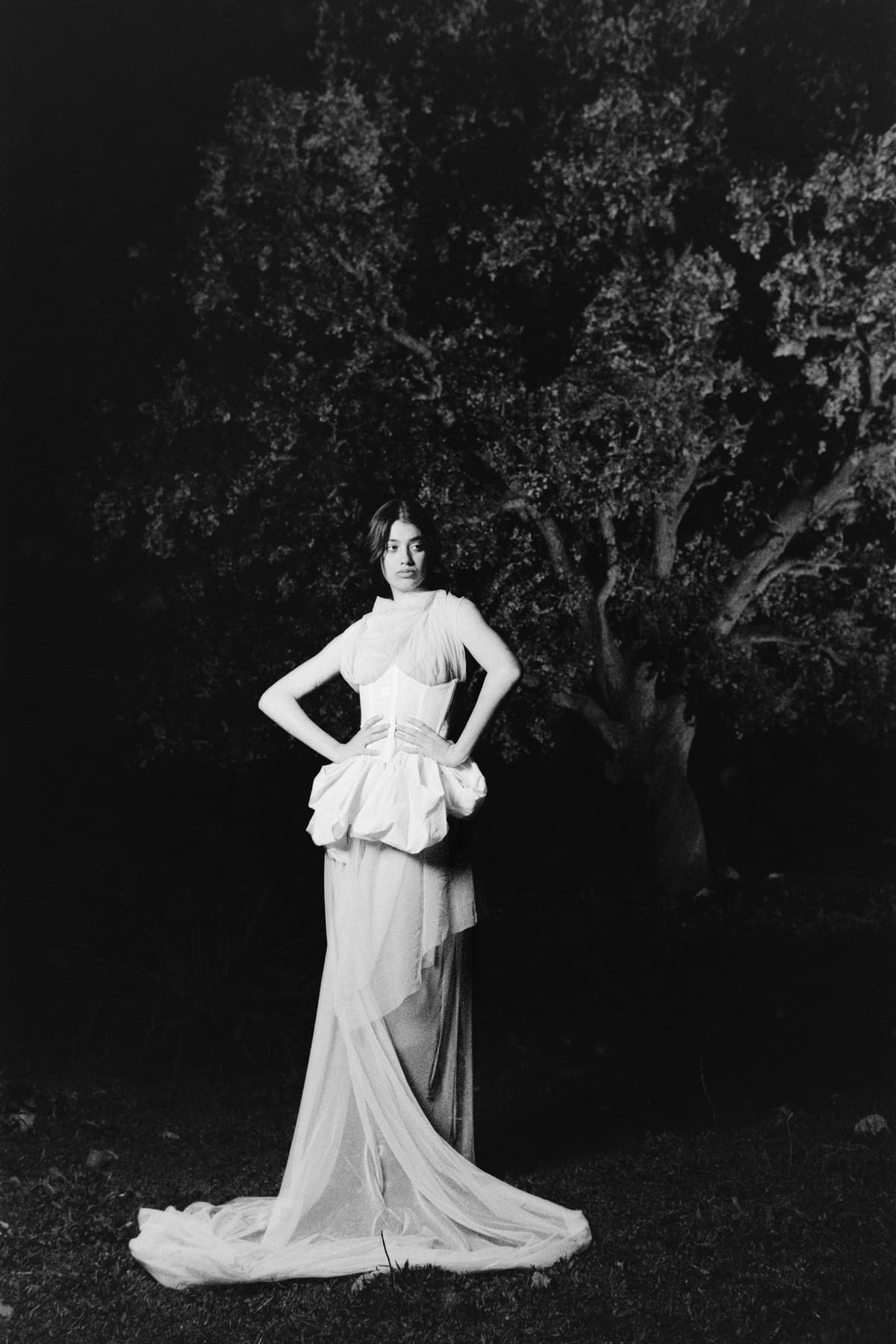 Retrato en blanco y negro de cuerpo entero frente al árbol